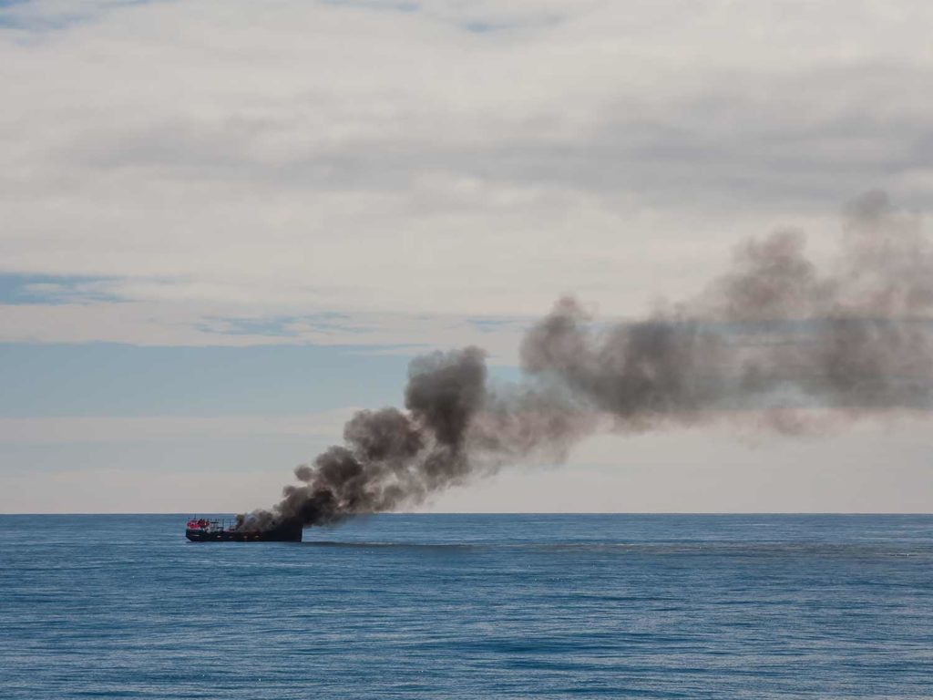 A boat on fire in the ocean.