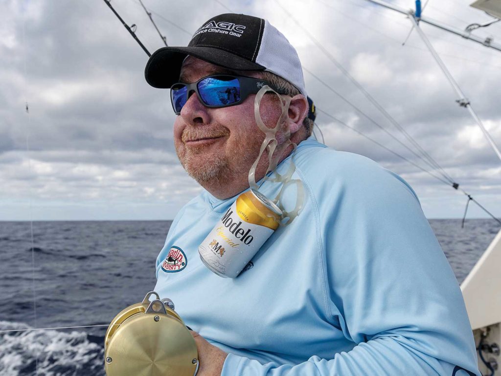 A sport-fishing angler standing with the ocean behind them.