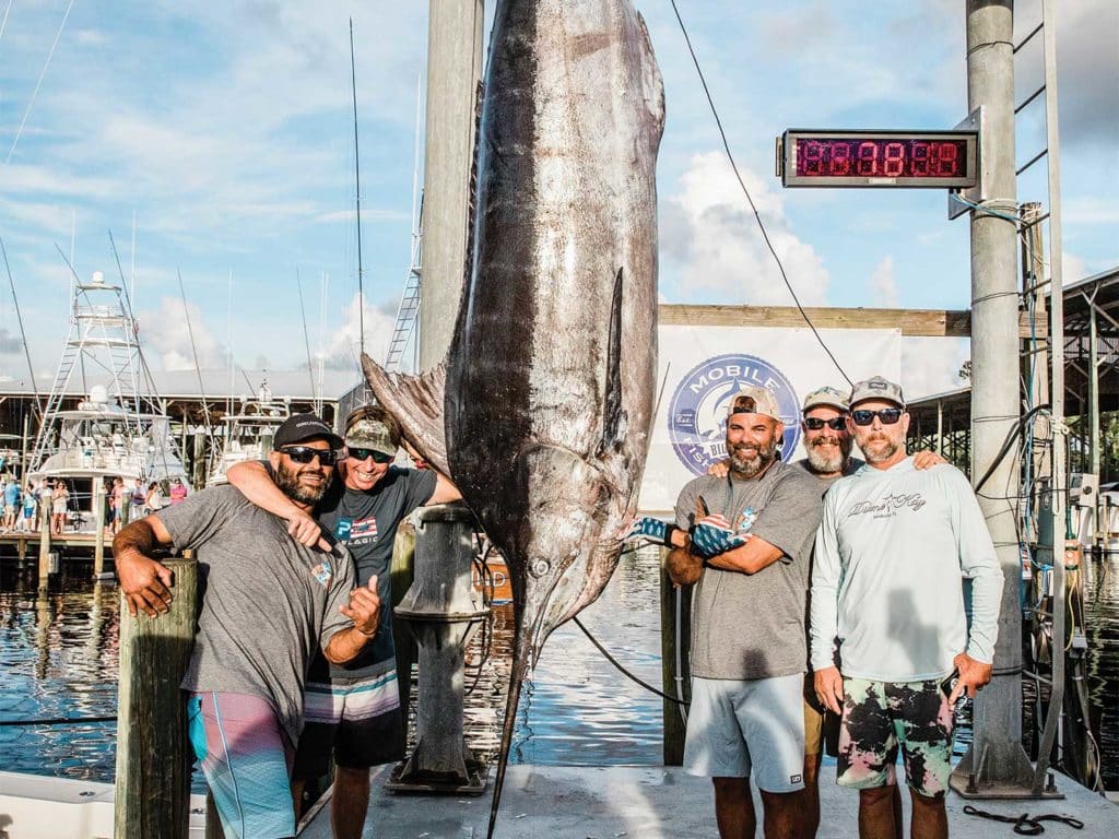 A sport-fishing team posing next to a large blue marlin.