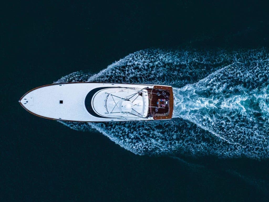 Aerial top-down view of a sport-fishing boat cruising across the open water.