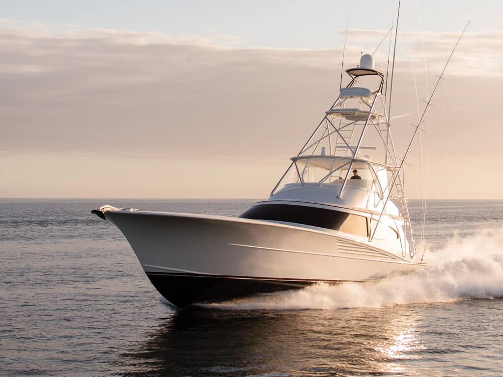 The custom Bayliss Boatworks sport-fishing boat cruises across the ocean at sundown. Warm lights and tones bounce off the modern touches of boat design.
