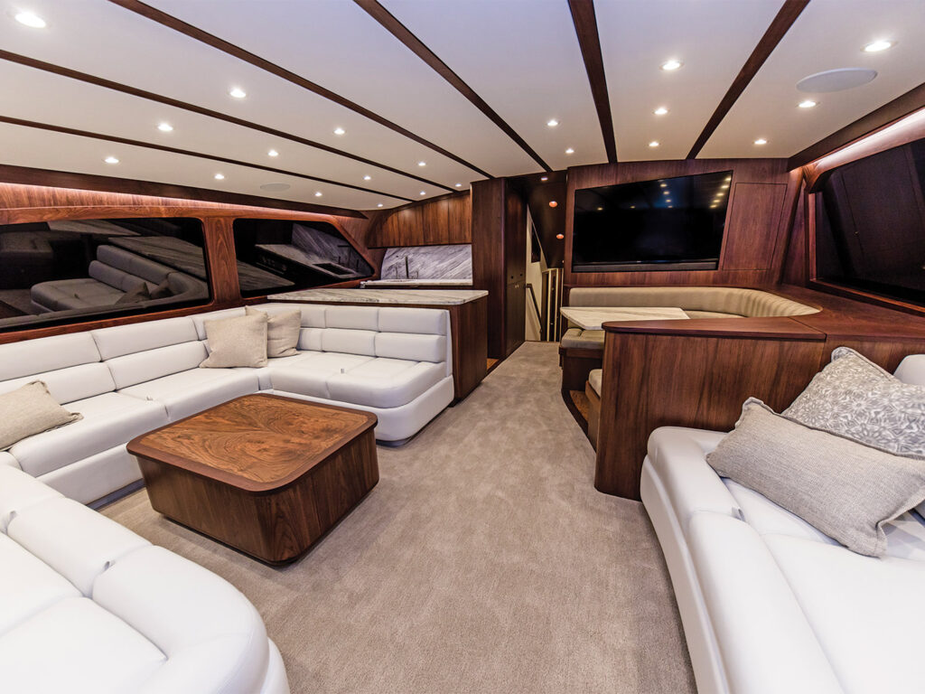 The interior seating and salon spaces of a custom Bayliss Boatworks sport-fishing boat. The clean interior is white lounge cushions, set against dark wood finishes.