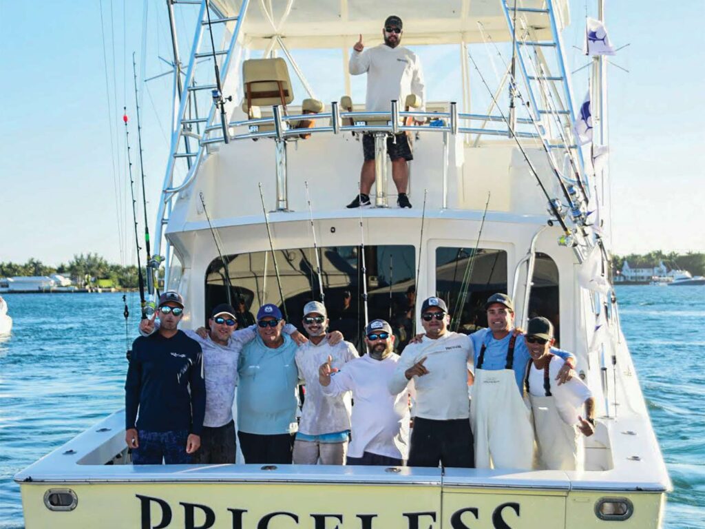 A sport-fishing team standing aboard a boat in the ocean.