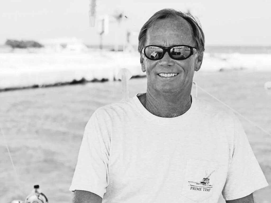 A black and white image of a sport-fishing captain against the ocean.