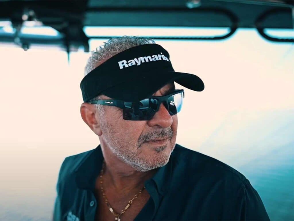 A boat captain wearing sunglasses and a Raymarine visor.