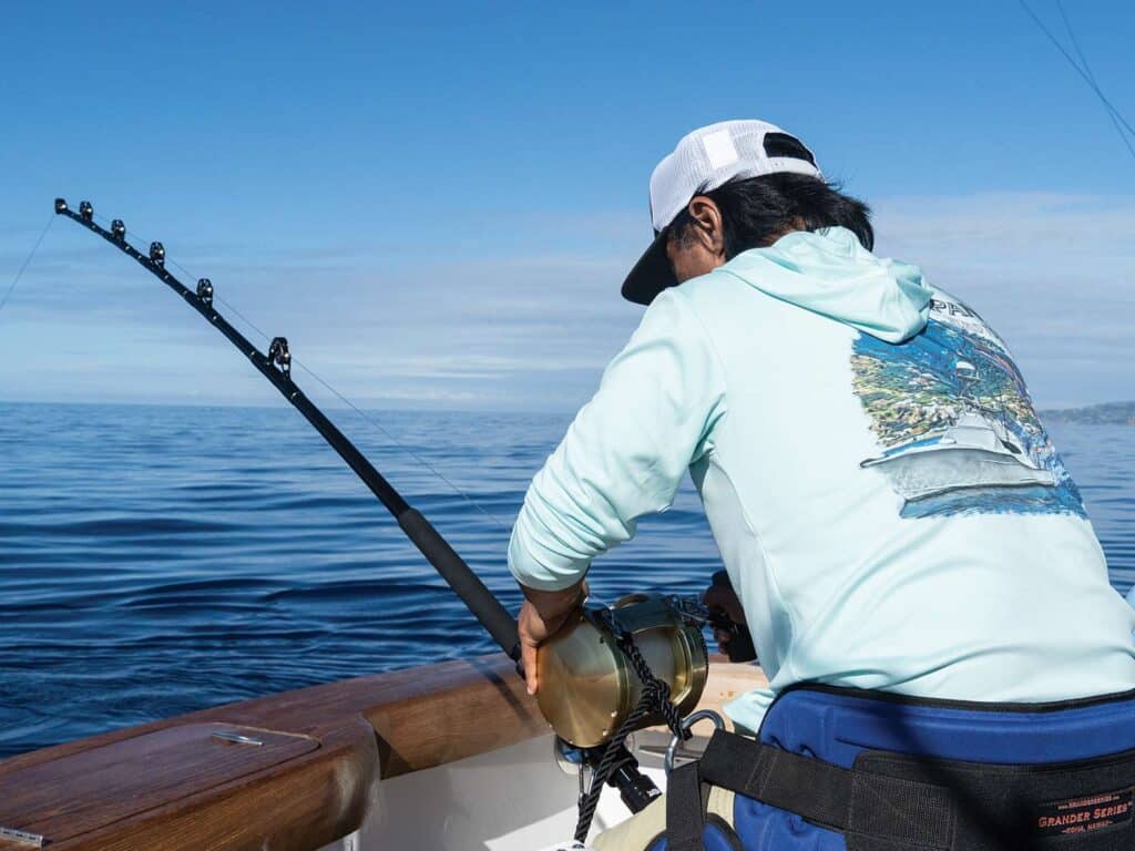 A sport-fisher fishing off a boat deck.