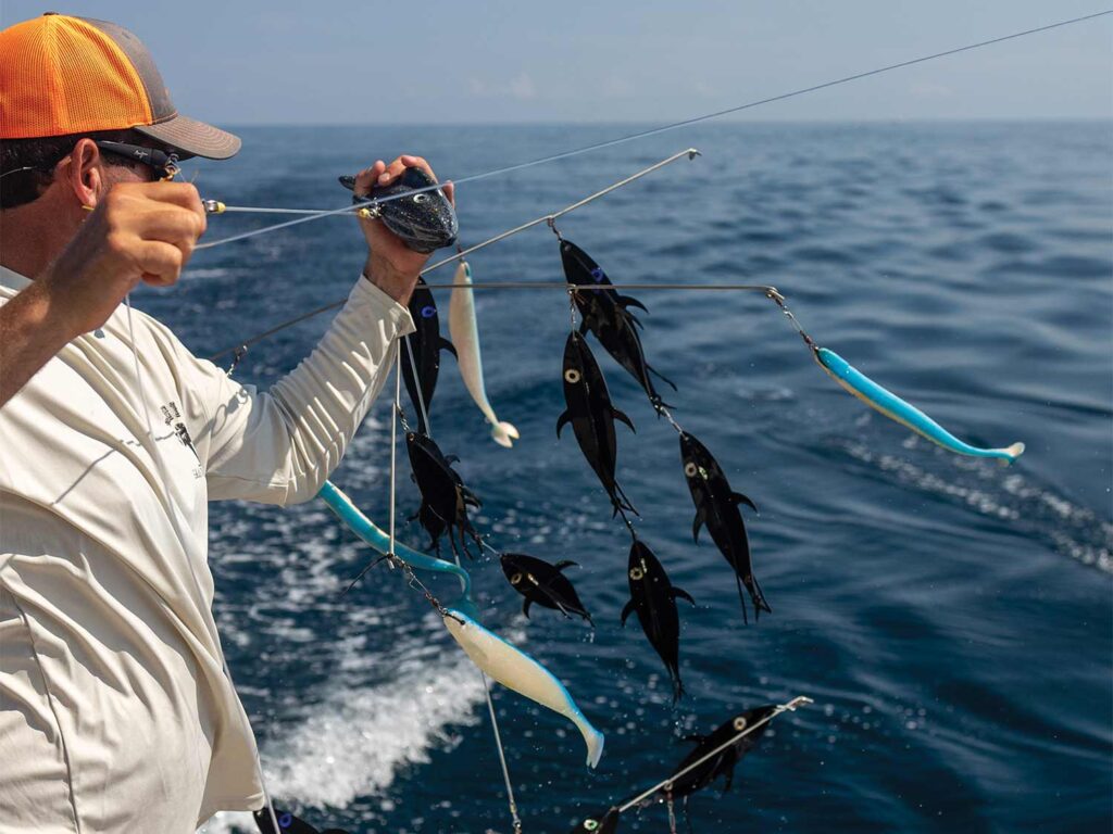 A sport-fishing angler lowering a fishing dredge into the water.