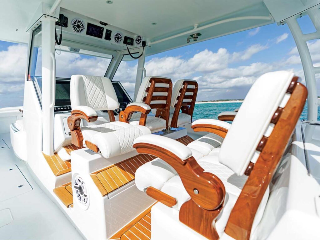The helm of a outboard sportfishing boat. The helm features wooden seats with white cushions.