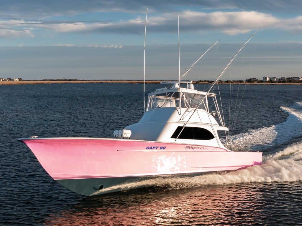 A pink-and-blue hulled boat cruises across the water.