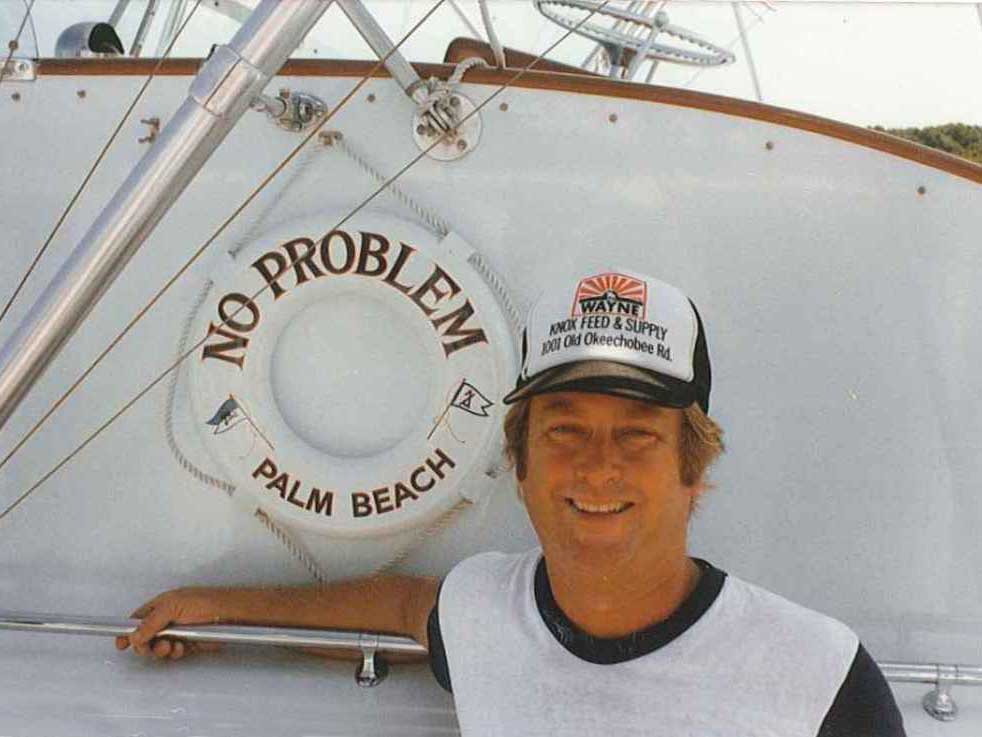 Photo of Capt. Jack Morrow standing next to a lifesaver with the boat name "No Problem" on it.