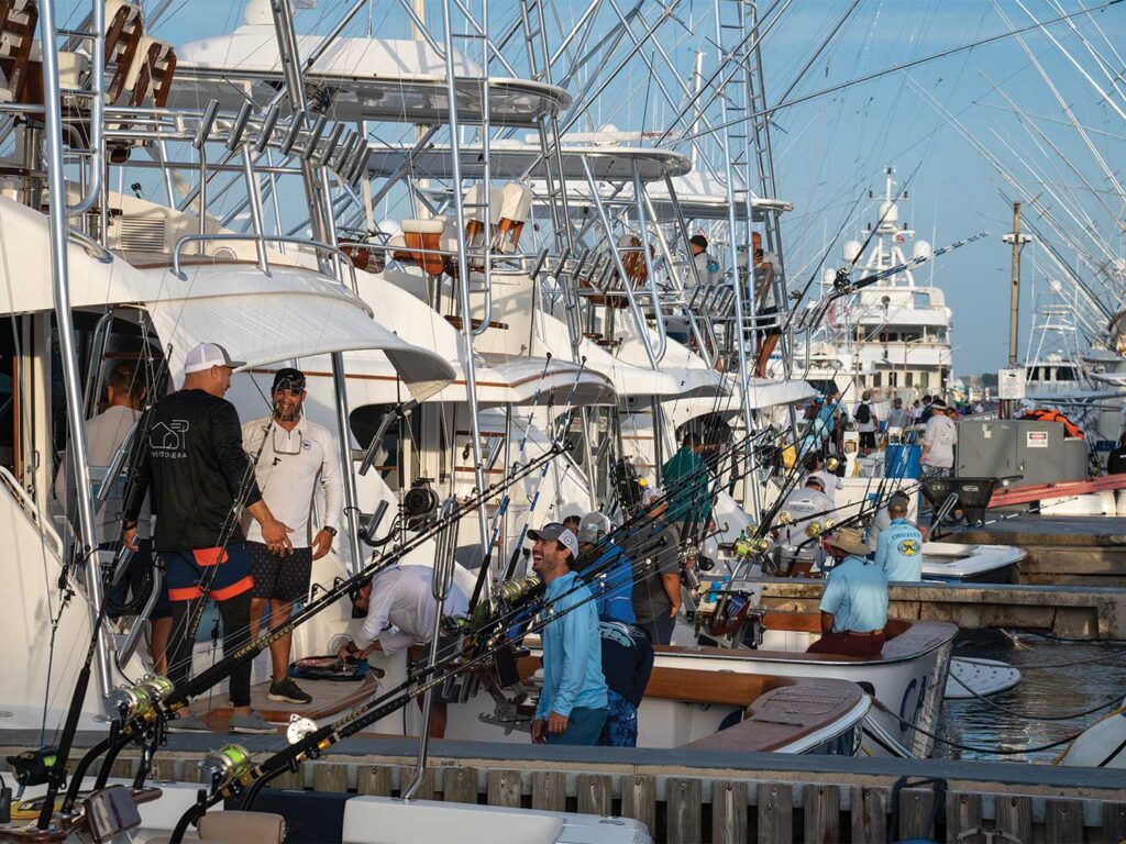 Several crews prepare their boats that are docked in a marina.