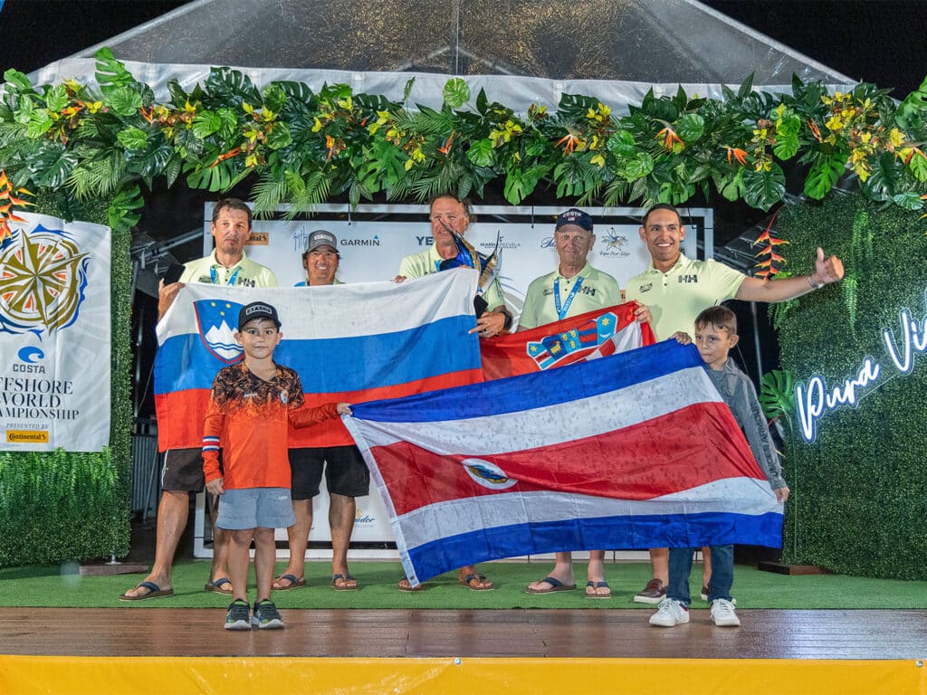 A sport-fishing team stands and accepts their prize at an awards ceremony stage.