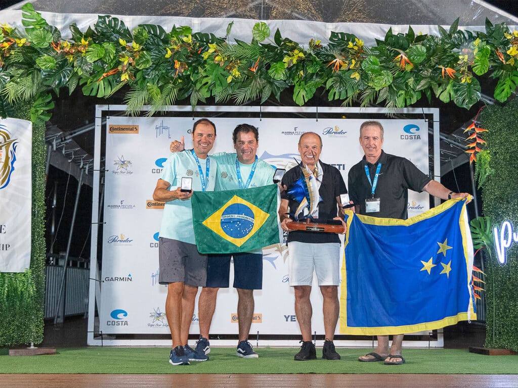 A sport-fishing team stands and accepts their prize at an awards ceremony stage.