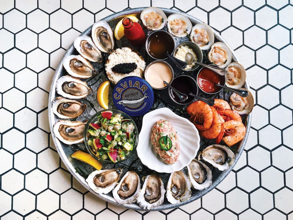Top-down view of a plate of raw oysters and other seafood.
