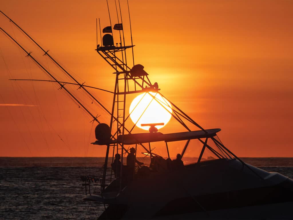A silhouette of a sport-fishing boat against the warm sunset.