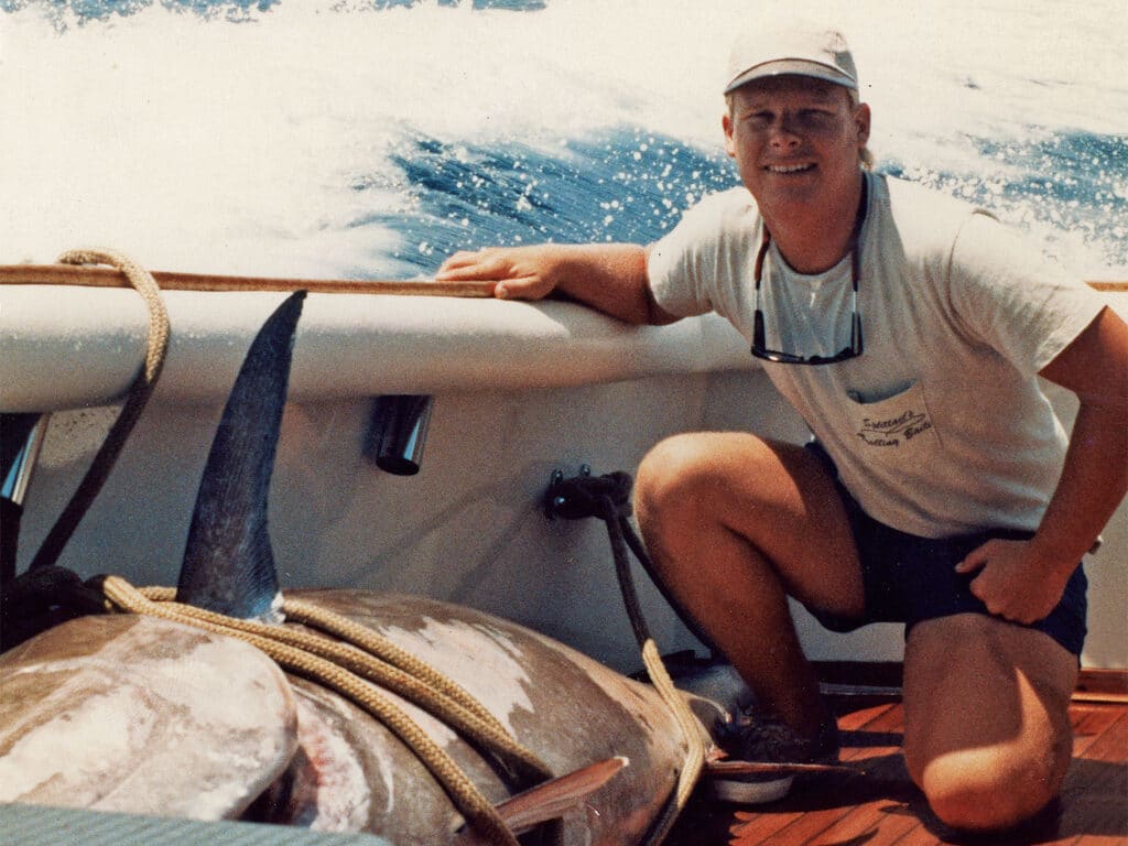Karl Anderson kneeling next to a large bluefin tuna in the cockpit of a boat.