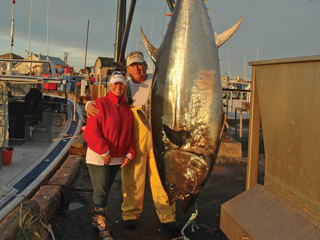 Karl Anderson and Debbie Lambert standing on the docks next to a large bluefin tuna.