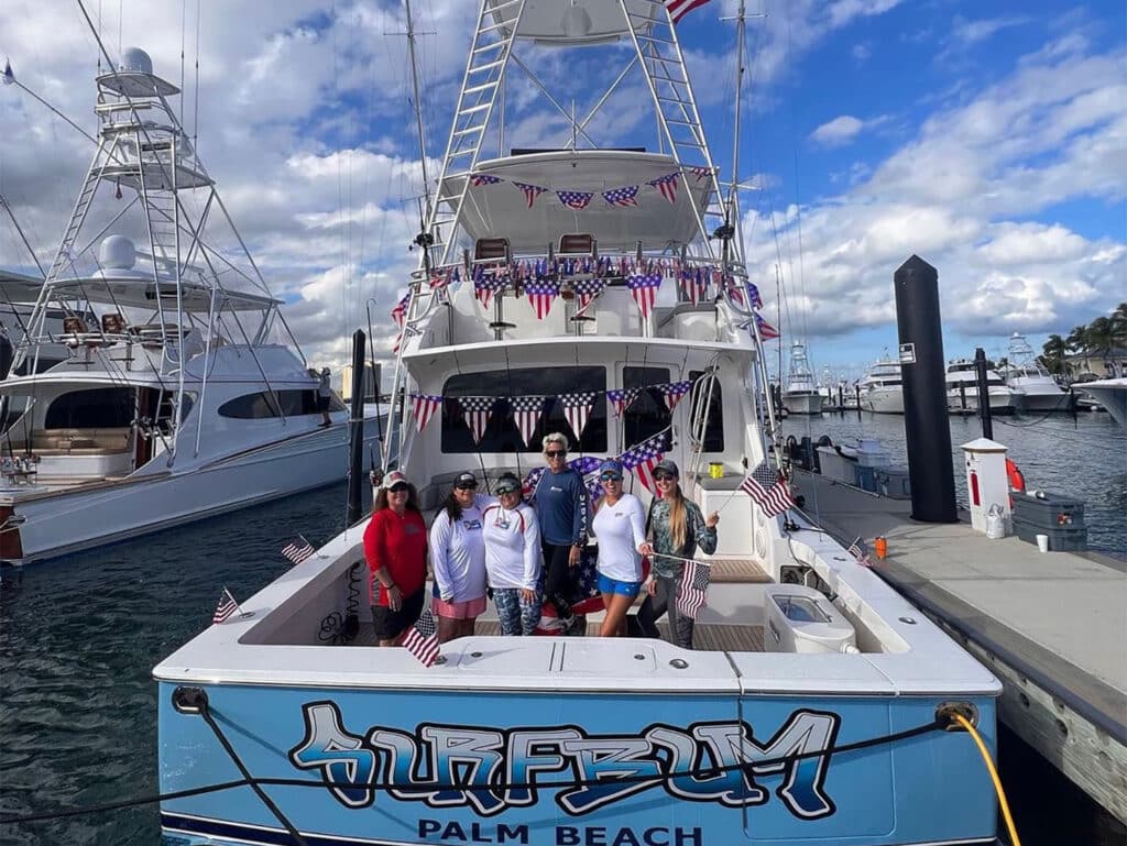 A sport-fishing team standing in the back of a sport-fishing boat.