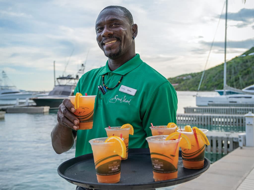 A Scrub Island Invitational attendant handing out cocktails on the boat docks.