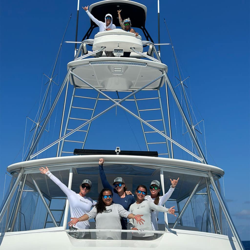 A ladies fishing team standing on a sport-fishing boat tower.