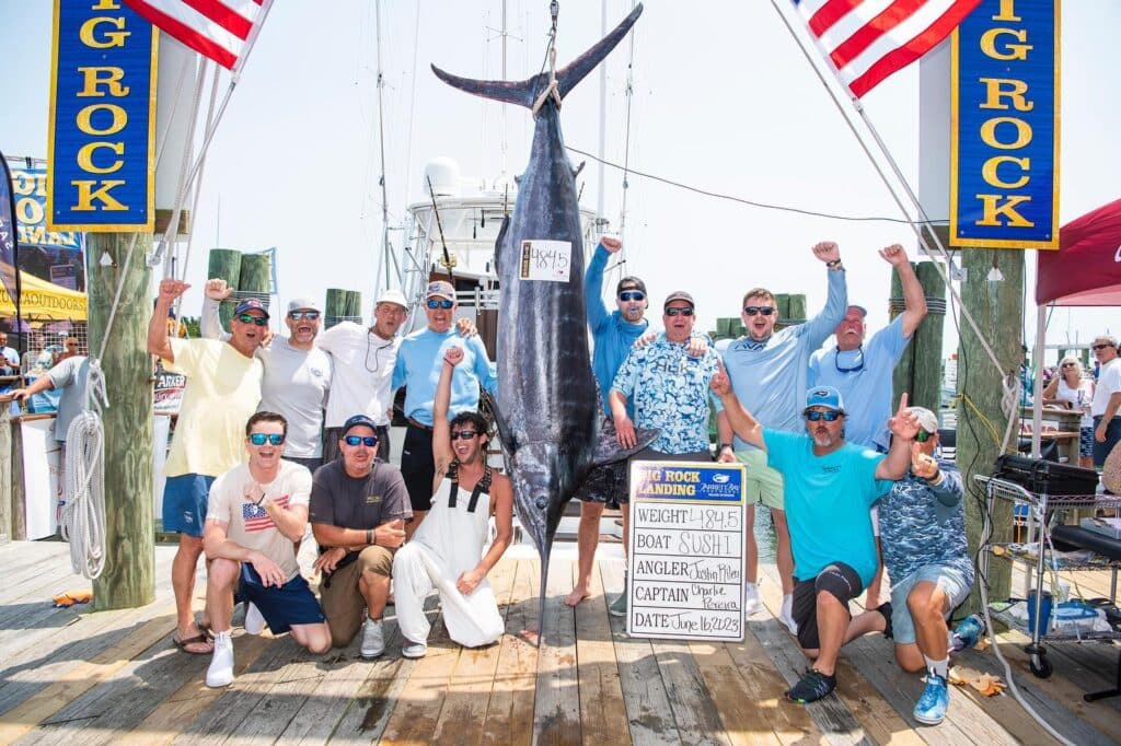 A sport-fishing team standing at the weigh station for a large marlin.