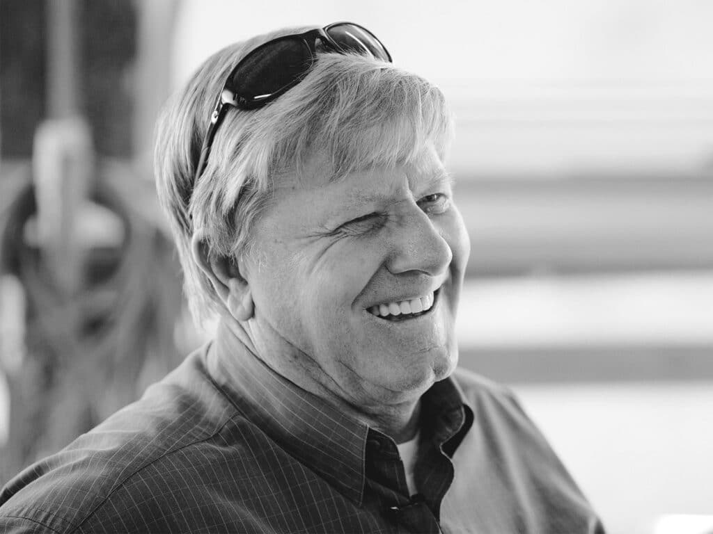 A black and white portrait of Capt. Paul Spencer in front of the ocean.