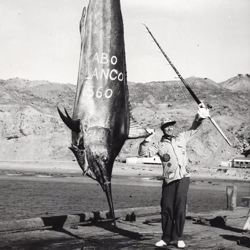 A black and white image of Alfred Glassell standing next of a large record black marlin.