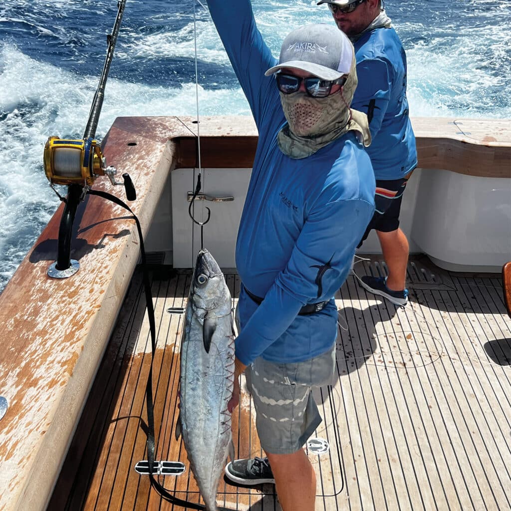 A sport-fishing angler holding up a large mackerel.