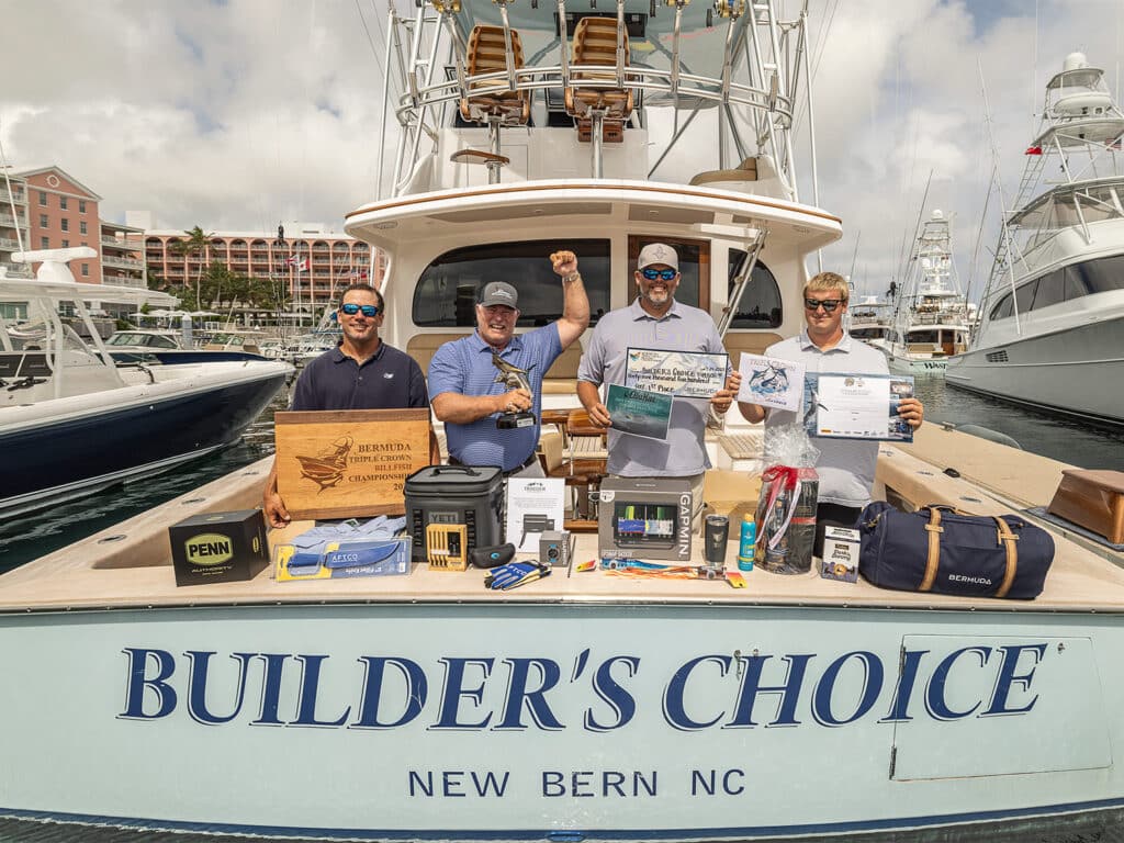 A sport-fishing team standing in the cockpit of a sport-fishing boat surrounded by their prize winninngs, trophies, and awards.