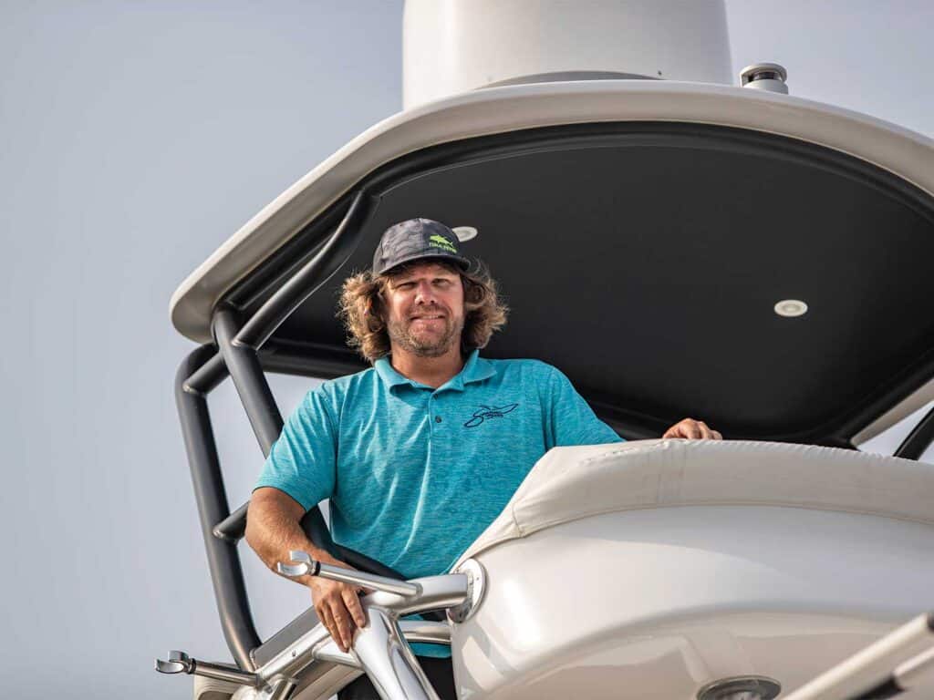 A man helms a sport-fishing boat.