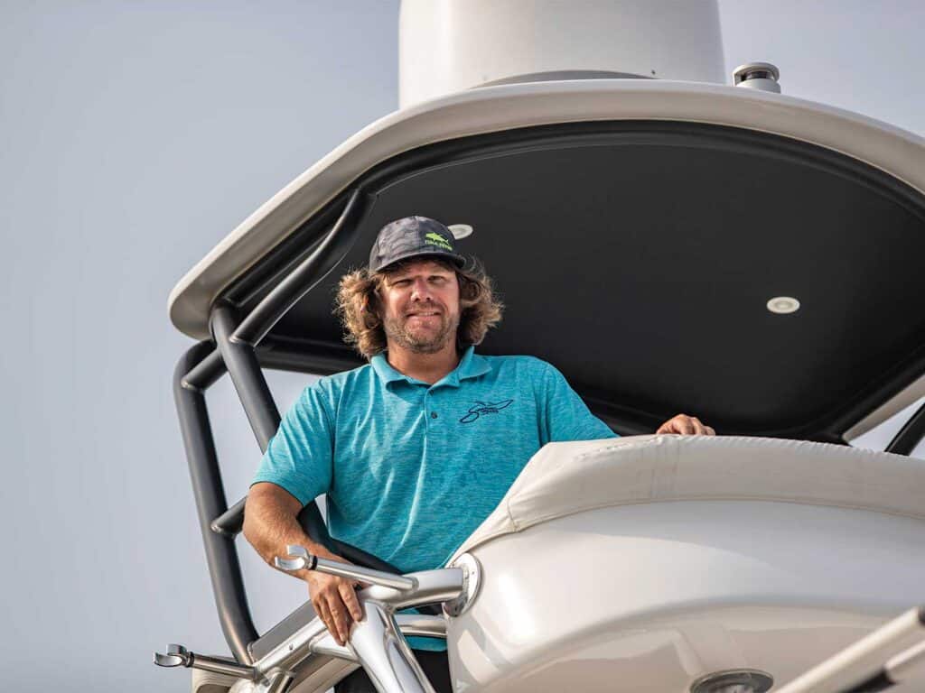 A man helms a sport-fishing boat.