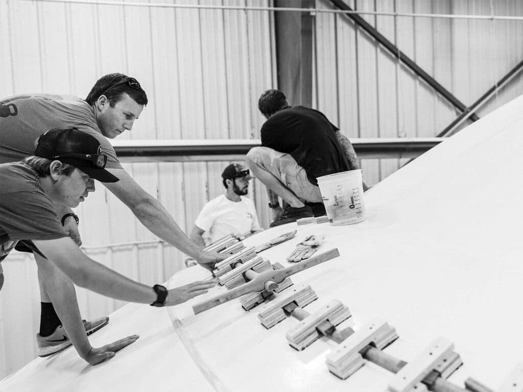 Several workers working on a boat hull.