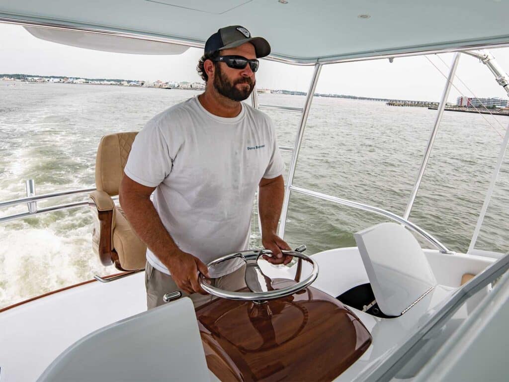 A man helms a sport-fishing boat.