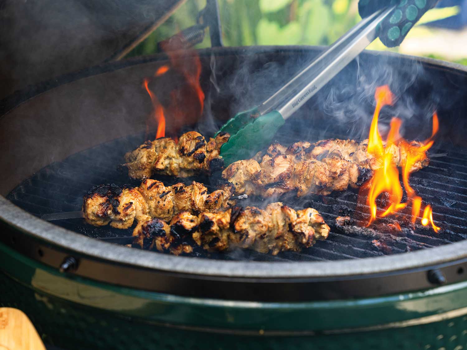 Chicken kebob skewers being seared over a flame inside a Big Green Egg grill.