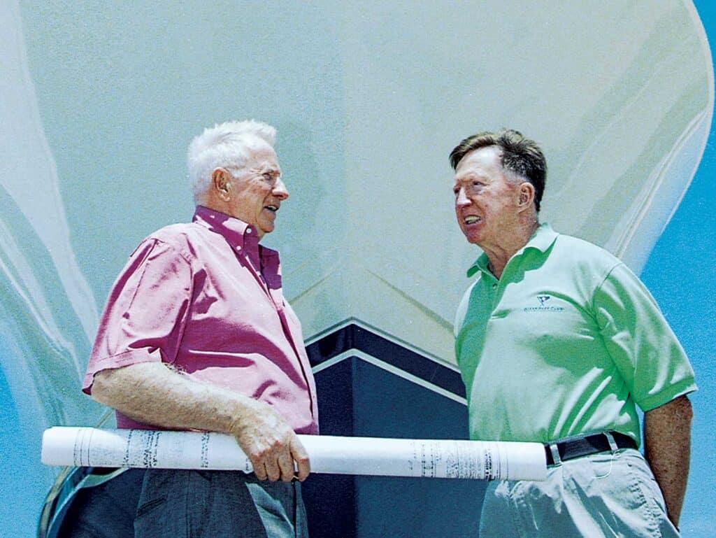 Bob and Bill Healey standing in front of a sport-fishing boat hull.