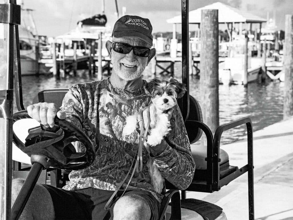 A black and white image of Capt. Skip Smith holding his small puppy.