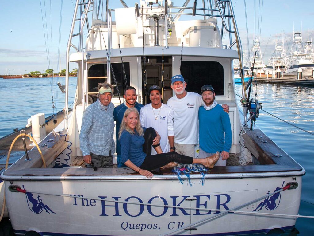 A sport-fishing crew led by Capt. Skip Smith standing and posing in the cockpit of the sport-fishing boat The Hooker.