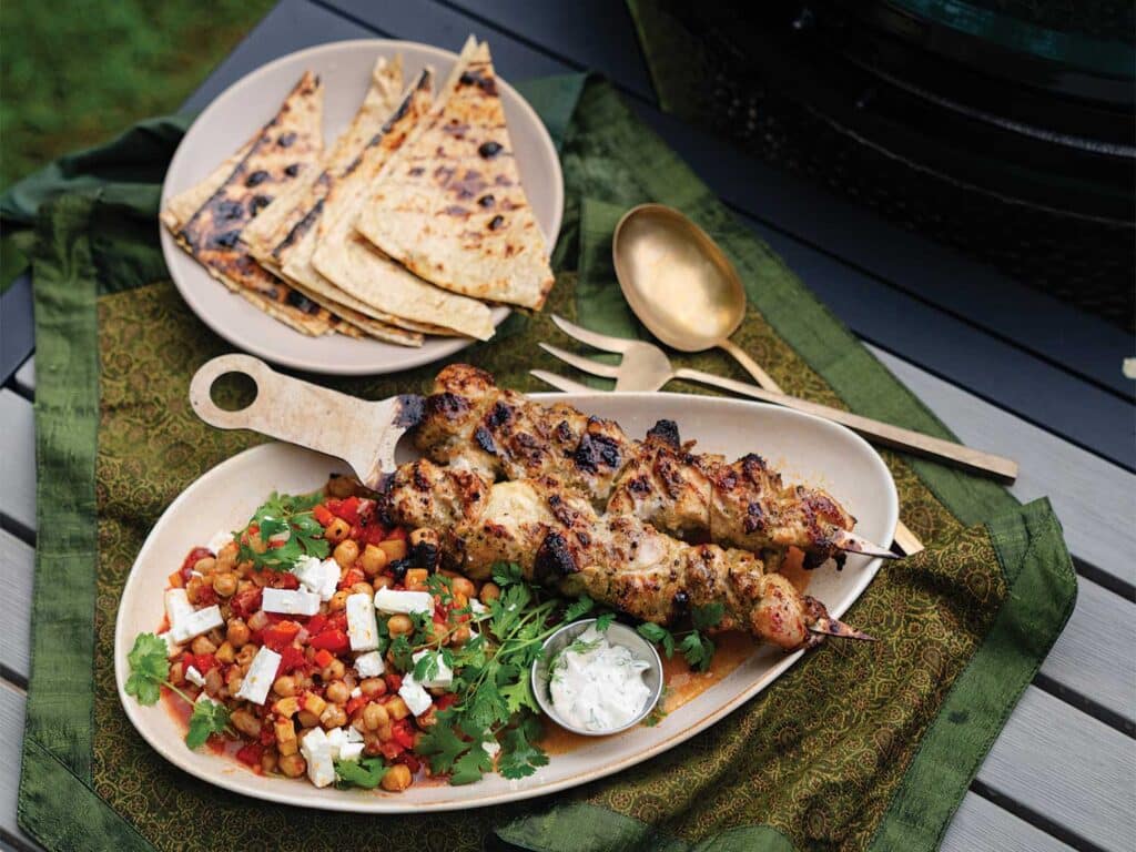 Labneb Chicken Kebobs with Harissa Chickpeas served in a bowl with slices of pita bread.
