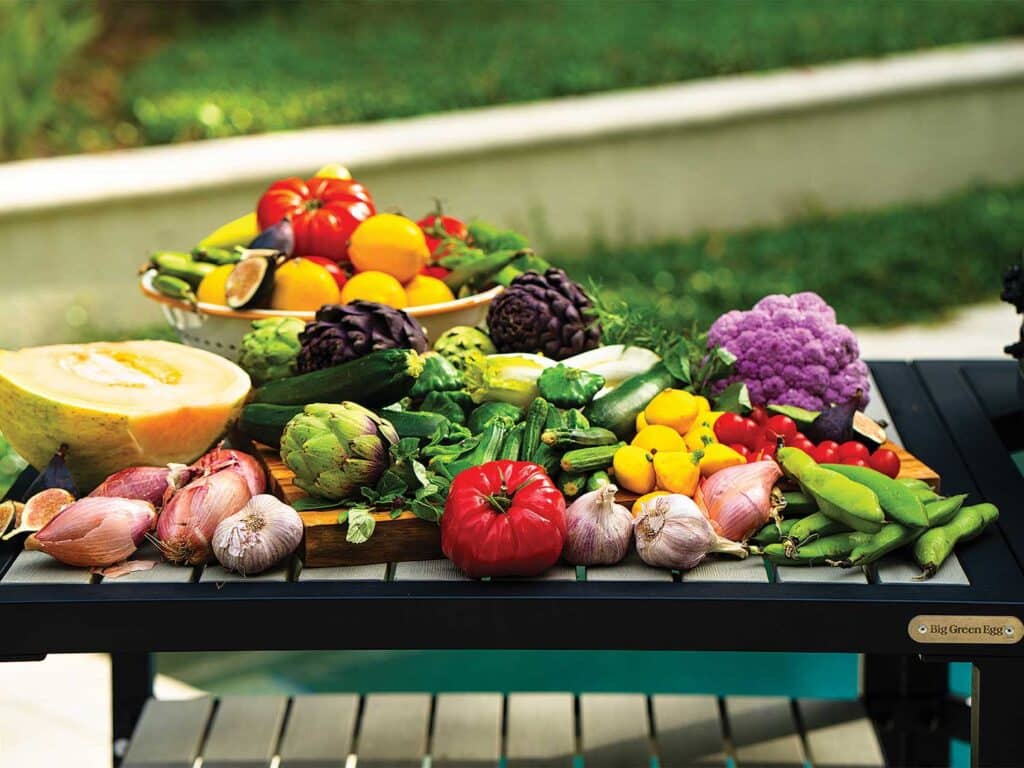An assorted arrangement of vegetables and greens on a picnic table.