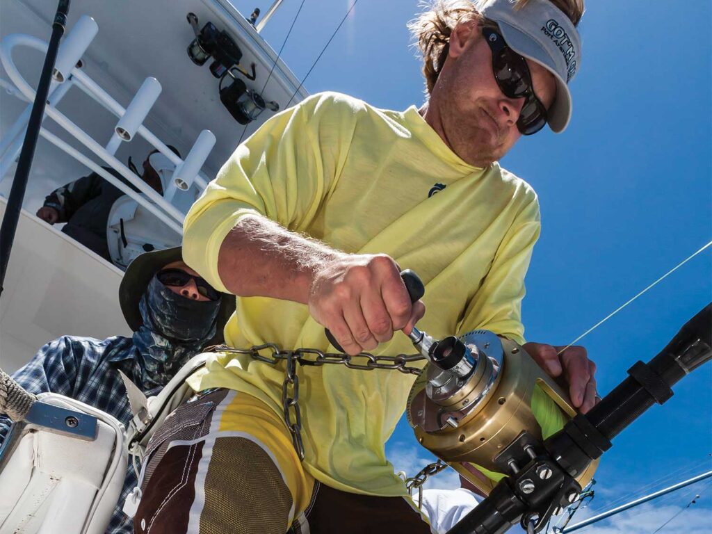 A sport-fishing angler reeling in a catch on heavy tackle.