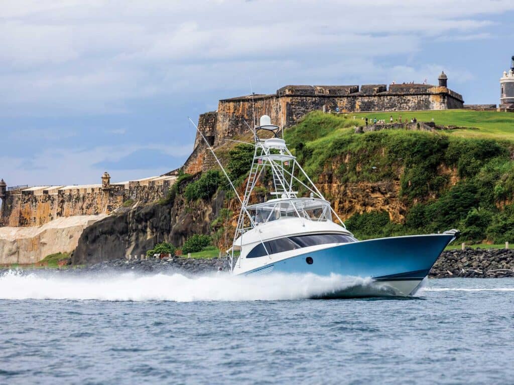 A sport-fishing boat cruising on the water past Fort Morro in San Juan
