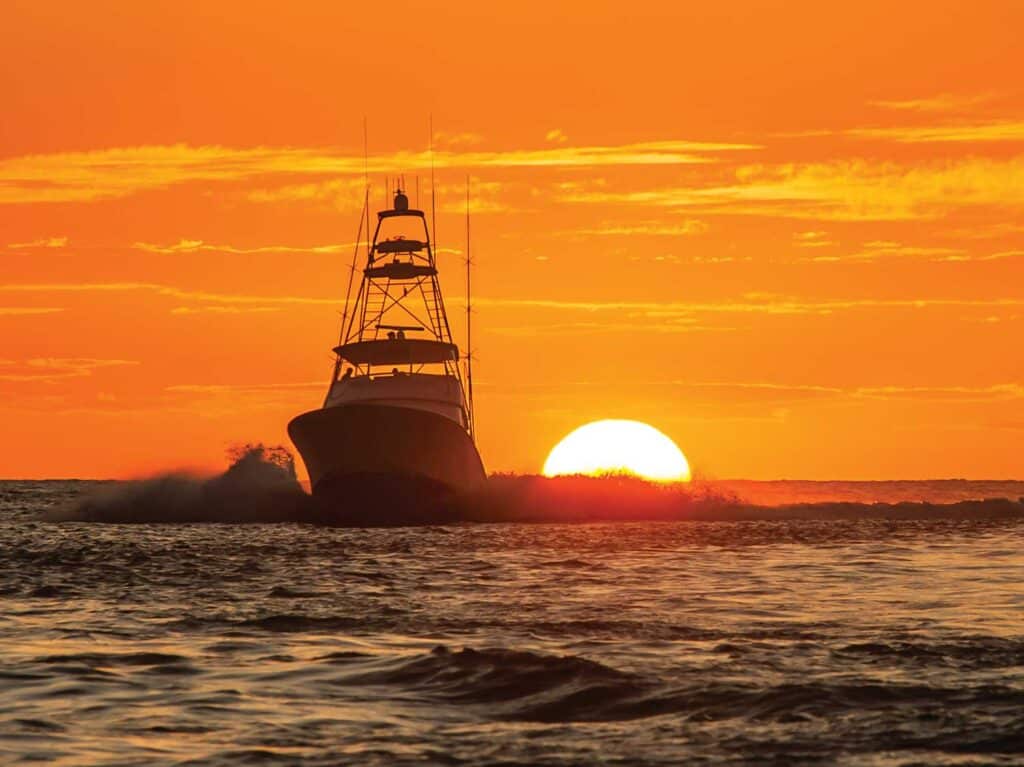 A silhouette of a sport-fishing boat against the setting sun.