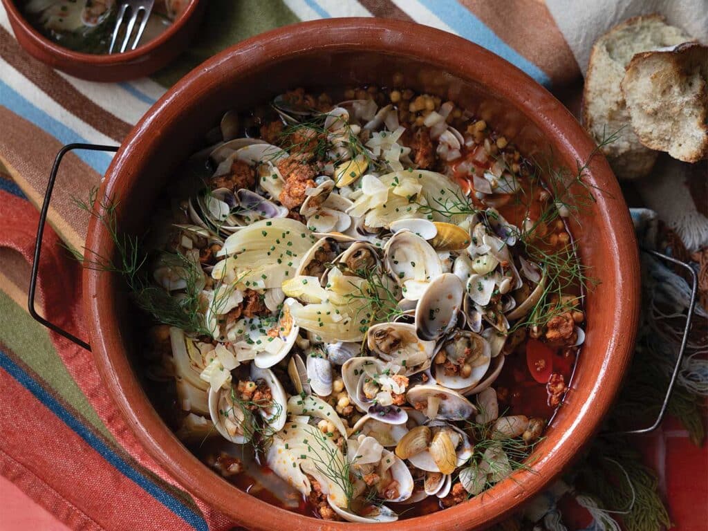 Steamed Clams Over Embers in a bowl and garnished with parsley and chives.