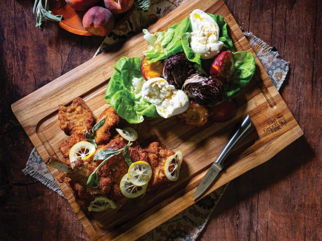 Veal Milanese with Peach and Radicchio Salad on a wooden cutting board.