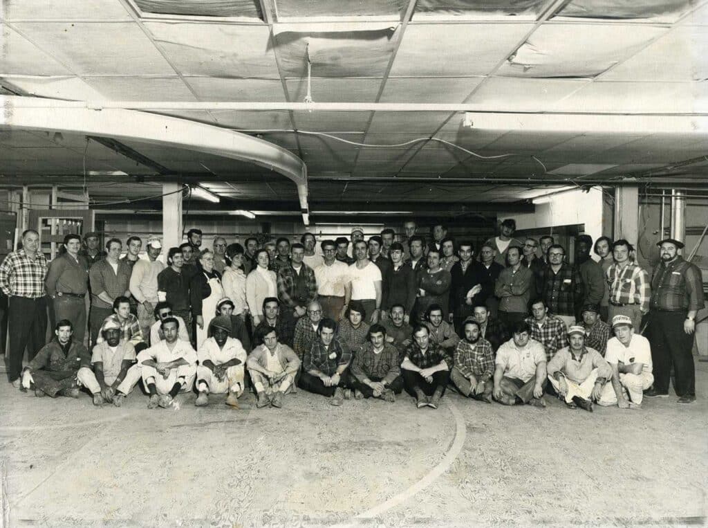 A group of shipwrights all grouped and posing for a vintage photo.