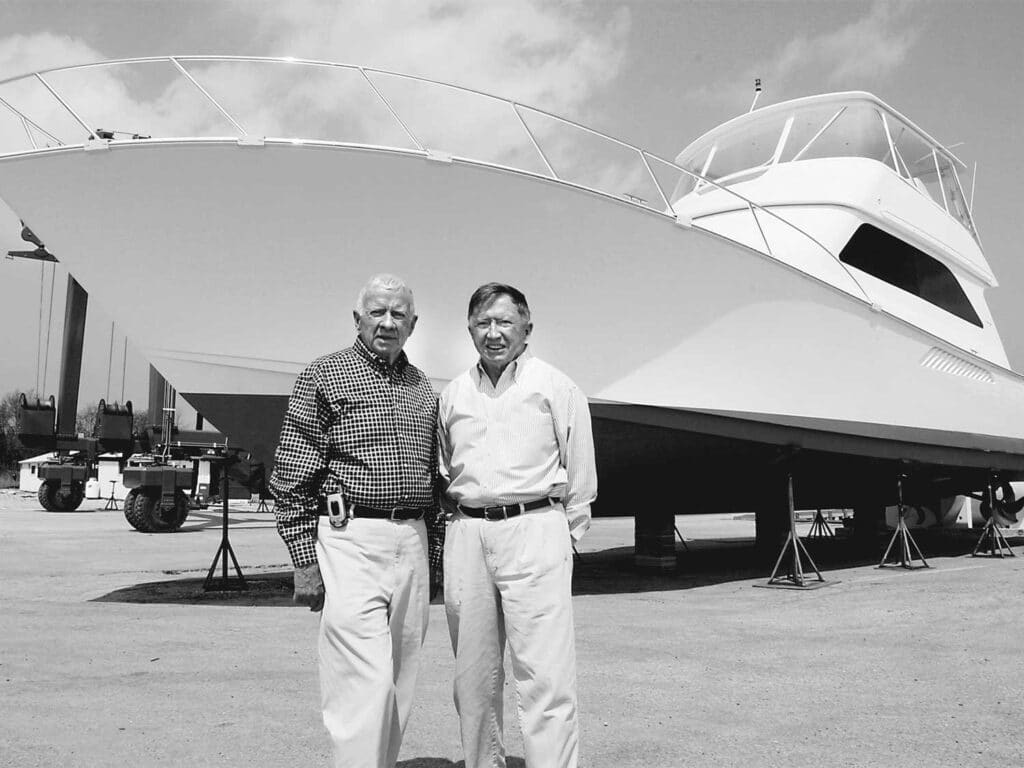 A black and white image of Bob and Bill Healey standing in front of a Viking Yacht hull.