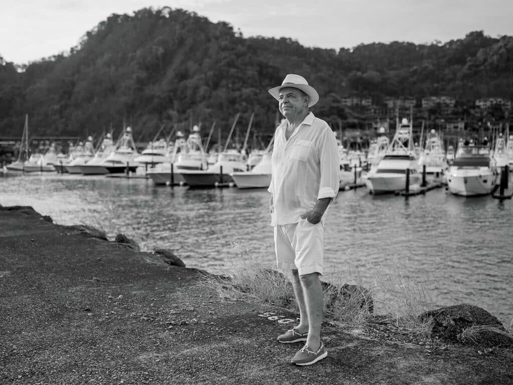 A black and white photo of Bill Royster standing in front of a marina full of sport-fishing boats.