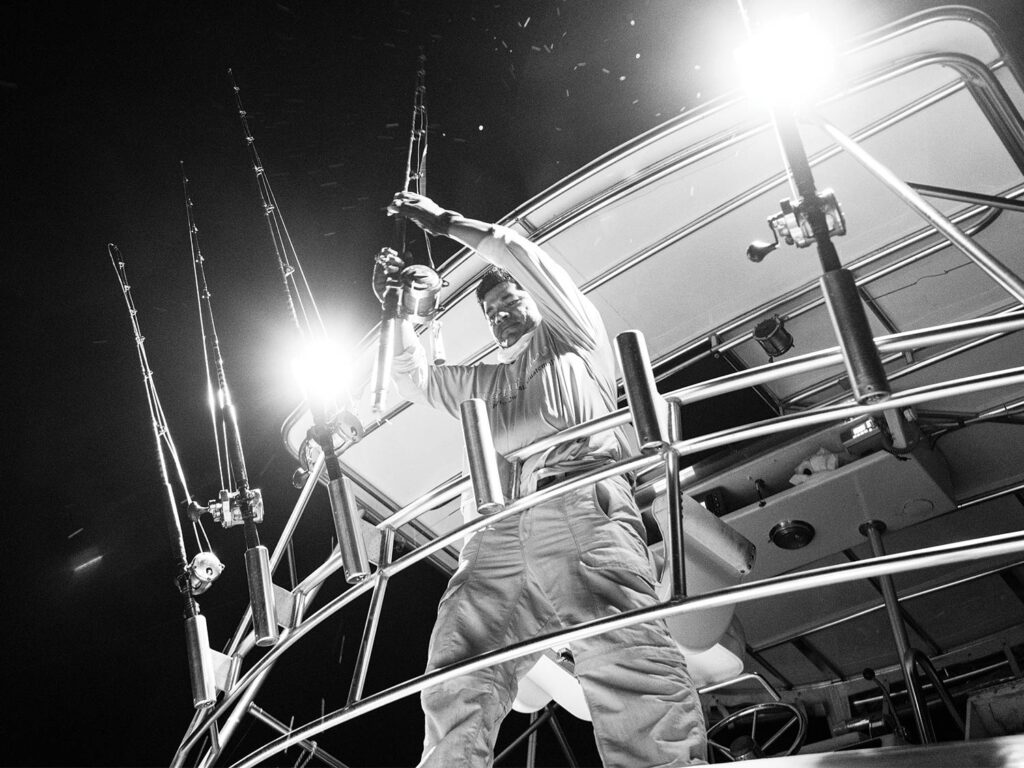 Black and white image of Capt. Eddie Bairez fishing at night.