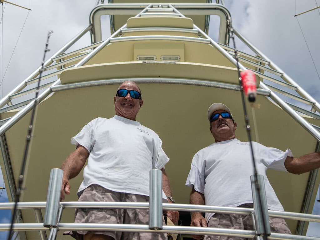 Two men stand in the tower of a sport-fishing boat.