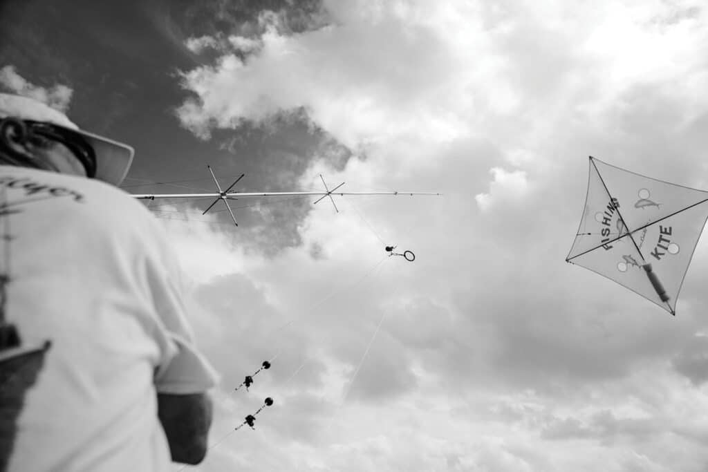 A black and white image of a person flying a kite in kite-fishing.
